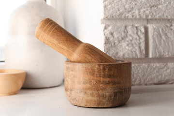 Wooden mortar and pestle on white table indoors, closeup