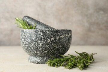 Stone mortar with rosemary and pestle on light table, closeup