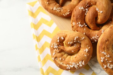Tasty pretzels with salt on white table, above view. Space for text
