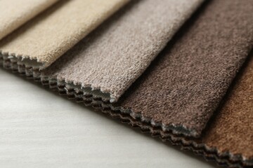 Samples of different fabrics on light wooden table, closeup