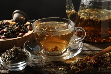Refreshing herbal tea and dry leaves on wooden table, closeup
