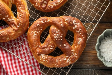 Tasty pretzels with salt on wooden table, flat lay