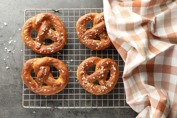 Tasty pretzels with salt on grey table, top view