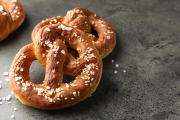 Tasty pretzels with salt on grey table, closeup. Space for text