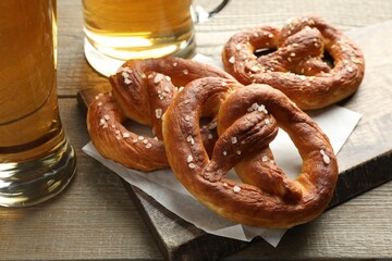 Tasty pretzels and beer on wooden table, closeup
