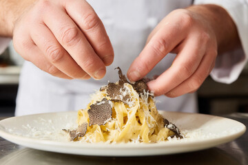 Chef preparing truffle pasta dish with fresh ingredients at restaurant