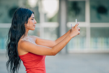 young latin girl or woman with summer clothes looking at her mobile phone or smartphone
