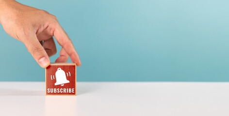 A man putting wooden block with bell icon and word subscribe. subscribe concept