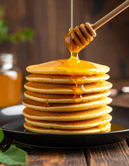 A drizzle of honey falling slowly onto a stack of golden pancakes served on a plate.