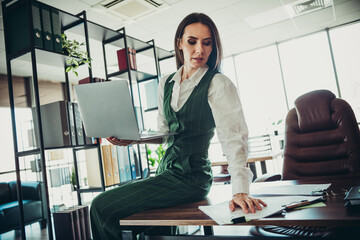 Professional businesswoman working on a laptop in a modern office, showcasing confident...