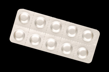 Medical pills in blister packaging, close-up, isolated on black background.