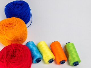 Colorful Yarn Balls and Thread Spools Arranged on a White Background