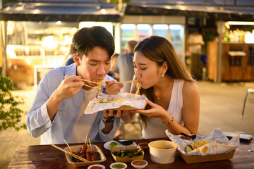 Two Asian Tourists Sharing Pad Thai at a Night Street Market