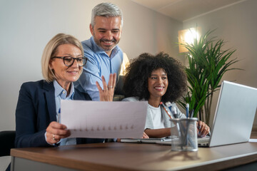 Three busy happy middle aged professional business man and two women executive leaders team using...
