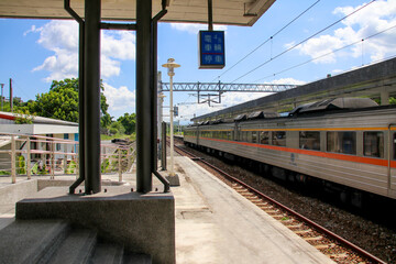 Fototapeta premium Taiwan May 21, 2024: A scenic view of a train at Fuli Station in Hualien, Taiwan, with clear sky and mountain background. Ideal for travel, transport, and rural tourism themes. Fuli Station