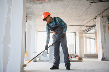 Construction worker applying waterproofing material on floor inside building