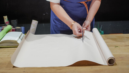 The florist cuts the wrapping paper with scissors. Close-Up.  Small Business.