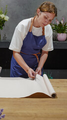 The florist cuts the wrapping paper with scissors. Close-Up.  Small Business.