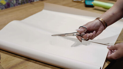 The florist cuts the wrapping paper with scissors. Close-Up.  Small Business.