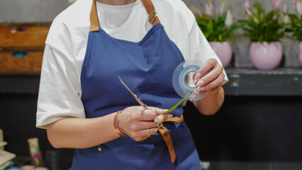A female florist measures ribbon for decoration. Small business.  Owner. Close-Up