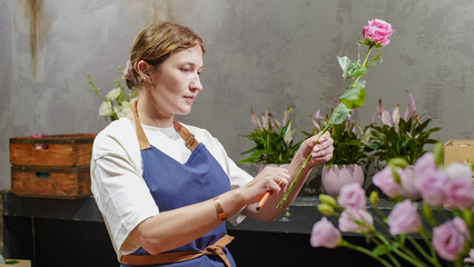 A florist makes a bouquet of pink roses in a flower shop. Small business.  Close-Up.