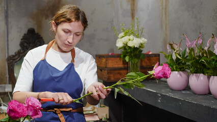 A florist makes a bouquet of pink roses in a flower shop. Small business.  Close-Up.