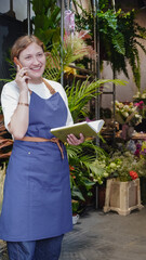 The florist is talking on the phone, smiling, and writing down business notes in a notebook. Small business. Close-Up.