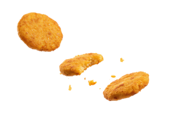 Three golden brown hash browns floating against a black background with scattered crumbs around them on transparent background