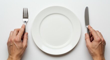 Empty white plate with fork and knife on a table. Hands holding utensils