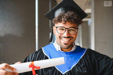 Happy graduate student showing his university diploma at graduation ceremony