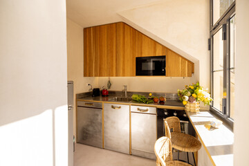 Bright kitchen with wooden cabinets, stone countertops, and fresh vegetables by the window. Ideal for editorial use, home design, or slow living content
