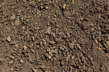 This detailed closeup showcases textured soil containing various rocks, making it perfect for landscaping and gardening projects