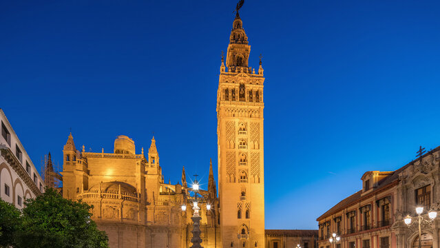 La Giralda and Seville Cathedral day to night timelapse glowing under the night sky.