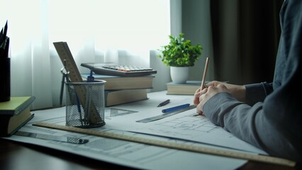 Architect Drawing at Wooden Desk with Tools and Books