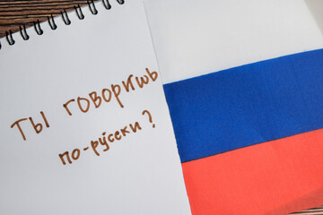 Concept of with question do you speak russian write on book and flag of russia isolated on Wooden Table.