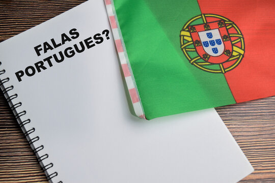 Concept of with question falas portugues write on book and flag of portugal isolated on Wooden Table.