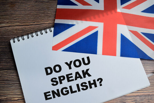 Concept of do you speack english write on book and flag of the united kingdom isolated on Wooden Table.
