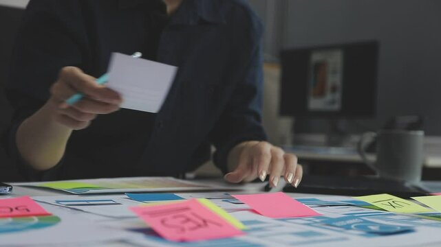 UX/UI designer working on wireframes for a website and mobile app prototype, surrounded by sketches of user-flow and design tools, in concept of website and mobile application design concept.