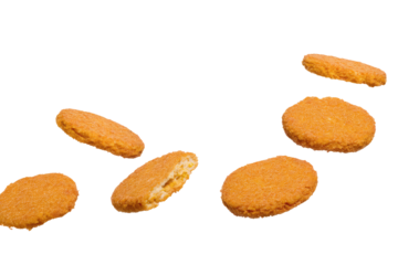 A scattered view of several golden brown breaded chicken patties on a black background in studio lighting