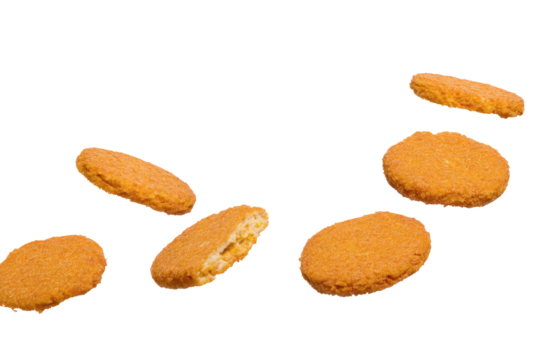 A scattered view of several golden brown breaded chicken patties on a black background in studio lighting