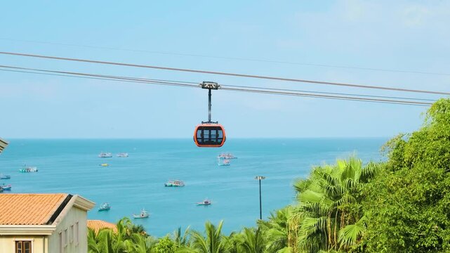 Modern cable car gondola ride over tropical seaside with fishing boats and blue ocean on Phu Quoc island, Vietnam at Sunset town. Hon Thom cable car cabin. Modern tourism technology and infrastructure