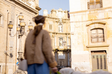 A woman smiles while looking up at historic architecture during a morning walk with her dog. The photo captures the essence of mindful travel, ideal for use in lifestyle, tourism, and wellness