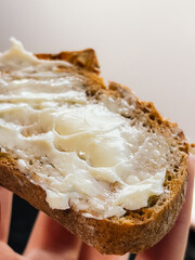 Bread with soft butter in morning light, bread on hand feels warm and rustic, bread brings sense of comfort, flavor and texture perfect for simple homemade breakfast. Toast slice spread with butter