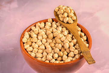 Wooden spoon with chickpeas in terracotta bowl