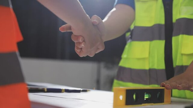Team engineer meeting for colleagues discussing and checks construction blueprints on new project at desk in office.
