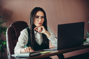 Experienced businesswoman working in her office, focusing on tasks with a professional demeanor,...
