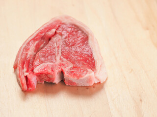 One fresh lamb loin chop on a wooden board. Expensive high quality meat product with bone for frying. © mark_gusev