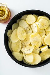 raw potatoes sliced ​​and spiced in the pan, ready to be roasted in the oven