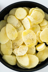 raw potatoes sliced ​​and spiced in the pan, ready to be roasted in the oven