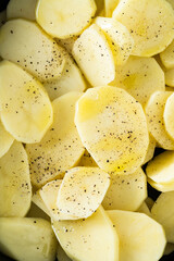 raw potatoes sliced ​​and spiced in the pan, ready to be roasted in the oven
